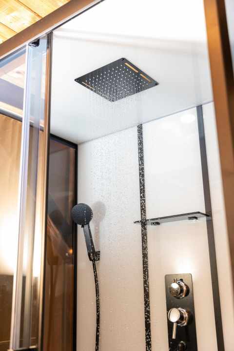 Moderne Regendusche und Handbrause in einem luxuriösen Badezimmer im Treehouse-Zelt im Holiday Park Mölke, Niederlande.