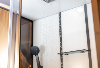 Moderne Regendusche und Handbrause in einem luxuriösen Badezimmer im Treehouse-Zelt im Holiday Park Mölke, Niederlande.
