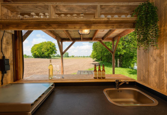 Vista dalla cucina di una tenda safari con lavello e bar sui campi al Holiday Park Mölke, Paesi Bassi.
