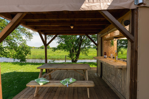 Überdachter Holzsitzbereich mit Bank und Bartheke beim Safari-Zelt im Holiday Park Mölke, Niederlande.