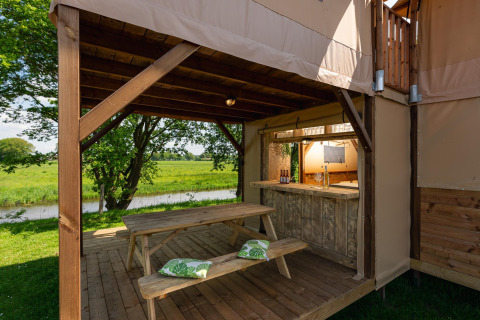 Gemütlicher Außenbereich am Treehouse-Zelt mit Picknicktisch und Flussblick im Ferienpark Mölke.