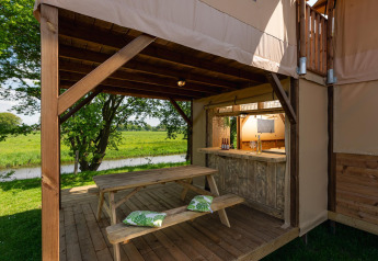 Udendørs opholdsområde ved Treehouse teltet med træbord, bænke og udsigt over floden på Mölke.