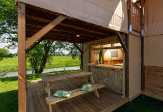 Buitenruimte bij de Treehouse tent met picknickbank en zicht op de rivier in Holiday Park Mölke.