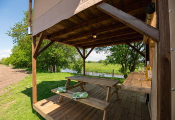 Veranda in legno coperta con tavolo da picnic al Treehouse tent, Holiday Park Mölke, Paesi Bassi.