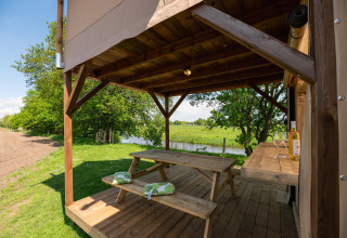 Overdekte houten veranda met picknicktafel bij het Treehouse safaritent, Holiday Park Mölke, Nederland.