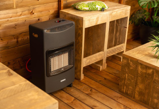 Innenraum eines Baumhauszeltes mit schwarzem Gasheizer, Holzmöbeln und Pflanzen im Holiday Park Mölke.