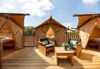 Safari-boomhuttent bij Holiday Park Mölke in Nederland met zonnig terras, comfortabele stoelen en slaapplekken.