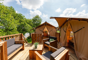 Außenbereich des Treehouse-Zeltes im Holiday Park Mölke, Niederlande, mit Holzterrasse und Sitzgelegenheiten.
