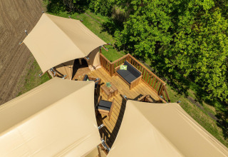 Vue aérienne de la tente safari Treehouse avec terrasse meublée au Holiday Park Mölke, Pays-Bas, entourée d’arbres.