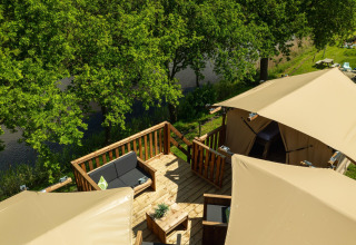 Tienda tipo casa en árbol en Holiday Park Mölke, Países Bajos, con terraza y vistas al río y árboles.