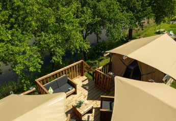 Tienda tipo casa en árbol en Holiday Park Mölke, Países Bajos, con terraza y vistas al río y árboles.