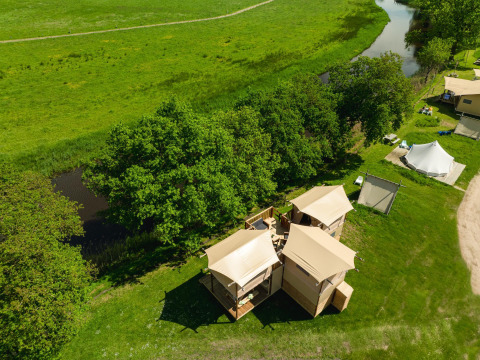 Vista aérea de la tienda Treehouse junto al río en Holiday Park Mölke, Países Bajos, rodeada de verde.