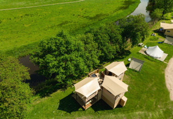 Vista aérea de la tienda Treehouse junto al río en Holiday Park Mölke, Países Bajos, rodeada de verde.