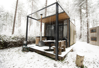 La pequeña casa Sweet Cabin con bañera de hidromasaje, rodeada de nieve en el bosque de Limburgo, Bélgica.
