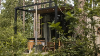 Casa pequeña Sweet Cabin con bañera de hidromasaje exterior, rodeada de bosque y naturaleza verde.
