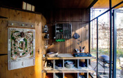 Acogedora cocina de tiny house con paredes de madera, utensilios y vista al bosque exterior.