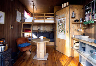 Kleine knusse woning met slaapzolder, houten meubels, compacte keuken en zithoek met tafel.