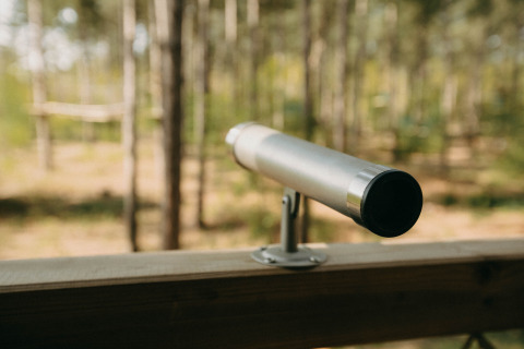 Telescopio en la terraza de una casa del árbol en Treetop de Cosy Cabins en el bosque de Limburg, Bélgica.