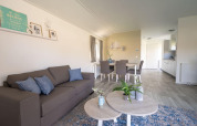Lichte, moderne leefruimte in de Velthorst-lodge bij EuroParcs Veluwemeer, Nederland, met sofa en eettafel.