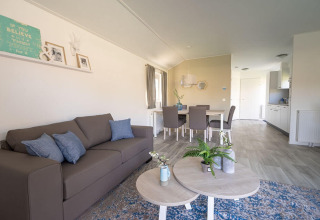 Lichte, moderne woonkamer in de Velthorst-lodge bij EuroParcs Veluwemeer, Nederland, met bank en eettafel.