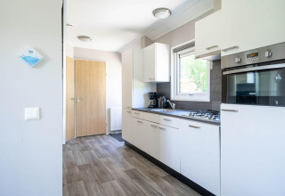 Moderne keuken in een Velthorst lodge bij EuroParcs Veluwemeer, Nederland, met witte kasten en inbouwoven.