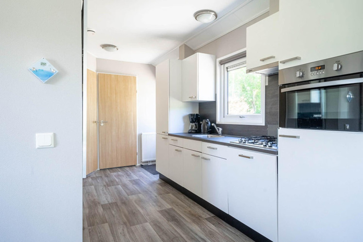 Cocina moderna en una cabaña Velthorst en EuroParcs Veluwemeer, Países Bajos, con muebles y horno empotrado.