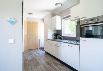 Moderne Küche in einer Velthorst Lodge bei EuroParcs Veluwemeer, Niederlande, mit weißen Schränken und Geräten.