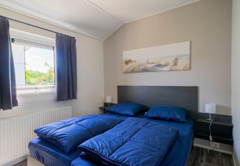 Schlafzimmer in der Velthorst-Lodge im EuroParcs Veluwemeer mit blauem Bettzeug und Wandbild.