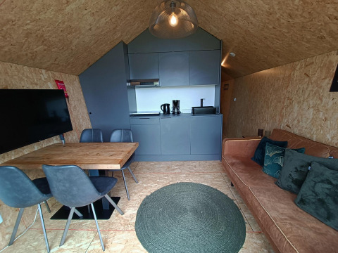 Intérieur de lodge moderne avec cuisine, table à manger, canapé et TV au Solo Retreat, EuroParcs Veluwemeer, Pays-Bas.