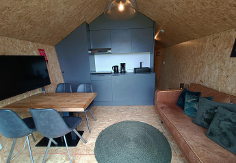 Interni moderni di una lodge con cucina, tavolo da pranzo, divano e TV a Solo Retreat, EuroParcs Veluwemeer, Paesi Bassi.