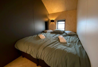 Acogedor dormitorio con cama doble, almohadas y suave iluminación en Solo Retreat en EuroParcs Veluwemeer.