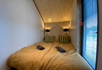 Camera con due letti, biancheria gialla e cuscini a righe al Solo Retreat presso EuroParcs Veluwemeer, Paesi Bassi.