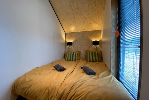 Chambre avec deux lits, draps jaunes et coussins rayés à Solo Retreat au EuroParcs Veluwemeer, Pays-Bas.