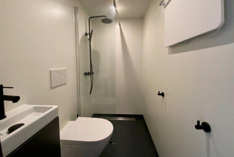 Baño minimalista y moderno con ducha, inodoro y lavabo en Solo Retreat, EuroParcs Veluwemeer, Países Bajos.