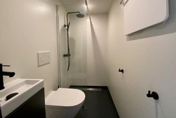 Baño minimalista y moderno con ducha, inodoro y lavabo en Solo Retreat, EuroParcs Veluwemeer, Países Bajos.