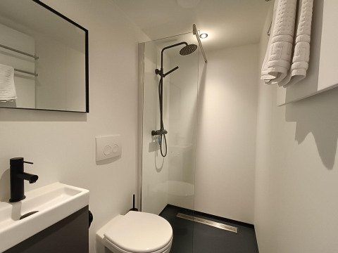 Bagno moderno e compatto con doccia, WC a muro e asciugamani al Solo Retreat di EuroParcs Veluwemeer.