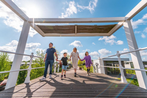 Gezin loopt over houten brug bij Solo Retreat in EuroParcs Veluwemeer, Nederland, op een zonnige dag.