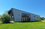 Moderne lodge Just Nature ved De Rijp i Holland, med skrå vægge, store vinduer og grøn græsplæne.