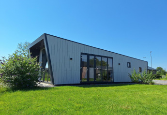 Moderne lodge Just Nature bij De Rijp in Nederland met schuine gevel, grote ramen en mooi groen gazon.