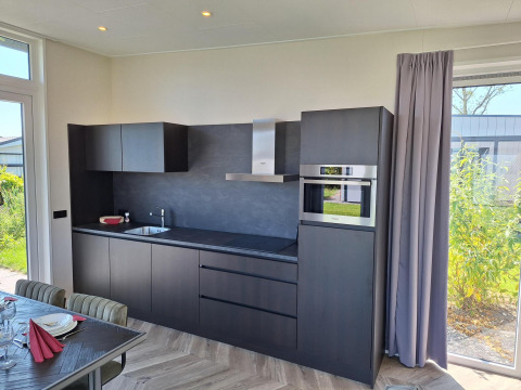 Moderne keuken in Just Nature lodge te De Rijp, Nederland, met zwarte kasten en grote ramen op de tuin.