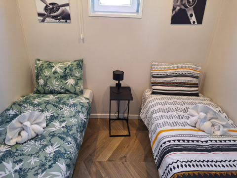 Chambre avec deux lits simples, linge de lit coloré, cygnes en serviette et déco moderne chez Just Nature.
