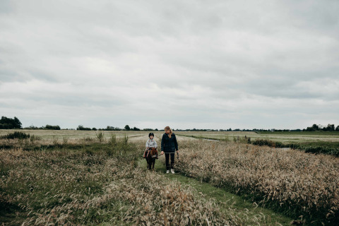 Een volwassene loopt met een kind op een pony door hoog gras bij Feather Down TaarTenTuin in Zuid-Holland.
