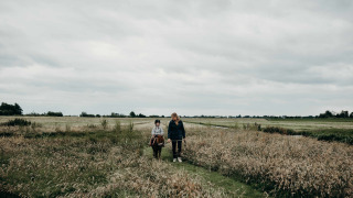 Un adulto camina con un niño montando un poni entre la hierba alta en Feather Down TaarTenTuin, Holanda del Sur.