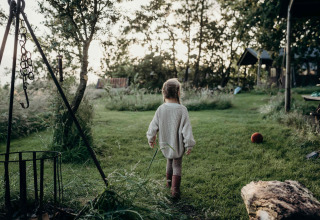Kind wandelt over gras bij Feather Down TaarTenTuin vakantiepark in Zuid-Holland, Nederland.