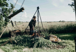 Enfant près d’un feu de camp au Feather Down TaarTenTuin, parc de vacances en Hollande-Méridionale, Pays-Bas.