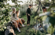 Kinderen en een volwassene bij een kampvuur op Feather Down TaarTenTuin vakantiepark, Zuid-Holland.