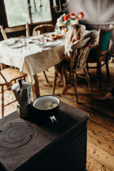 Fornuis met koffiekan en eieren, vage achtergrond met kind aan eettafel in Feather Down TaarTenTuin.