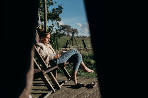 Mujer relajándose y leyendo en una tumbona de madera, Feather Down TaarTenTuin, Holanda Meridional, Países Bajos.