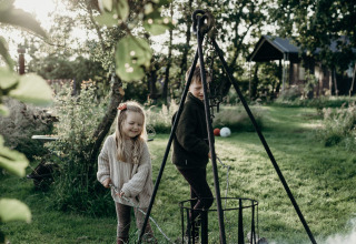 Twee kinderen rond een kampvuur bij Feather Down TaarTenTuin, een vakantiepark in Zuid-Holland, Nederland.