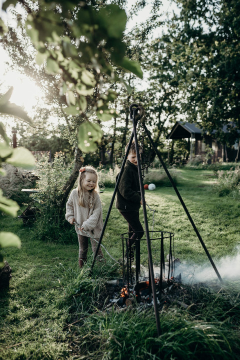 Zwei Kinder genießen die Natur am Lagerfeuer im Feather Down TaarTenTuin Ferienpark in Südholland, Niederlande.